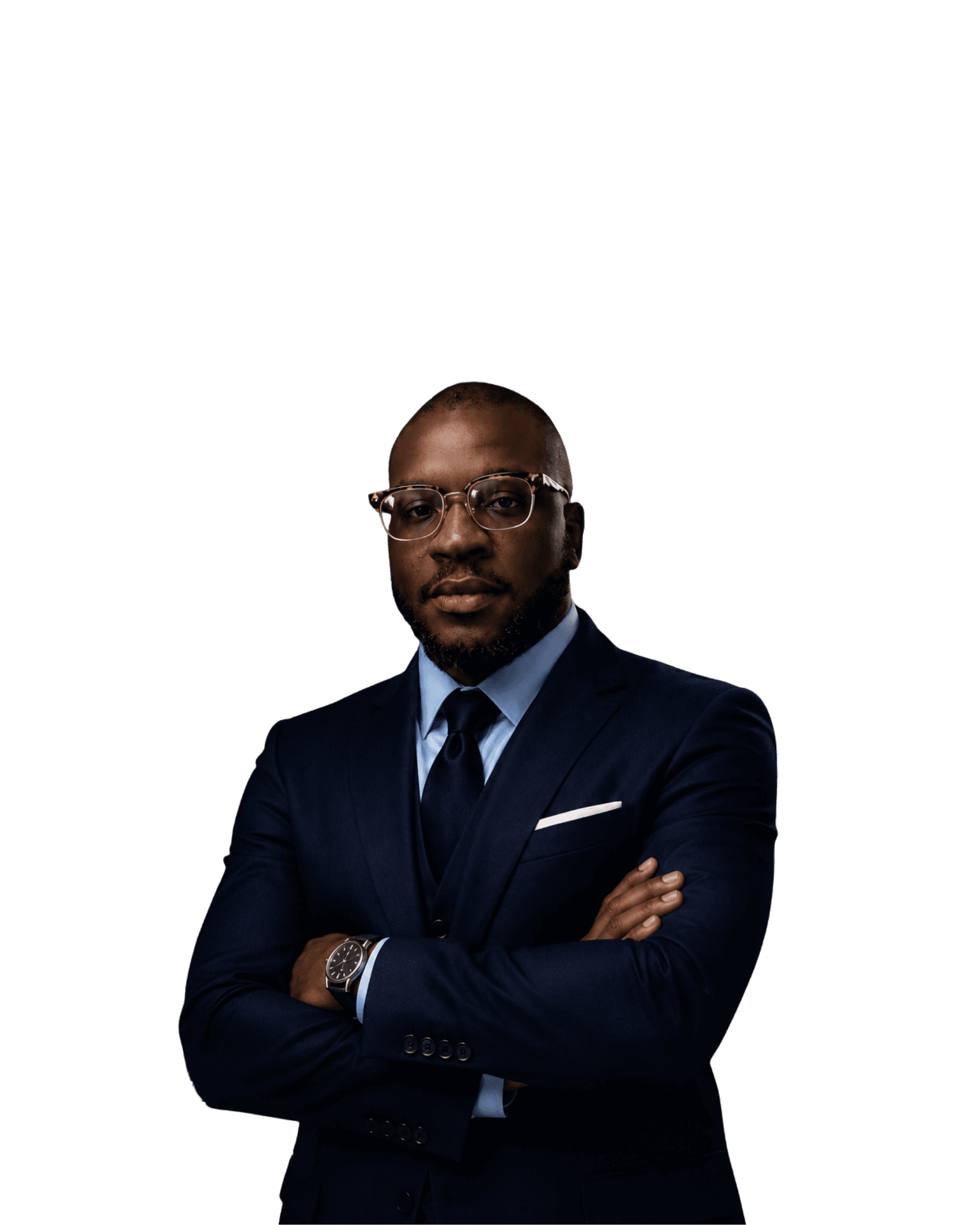 Jed Ibekwe standing with his arms crossed, in a dark navy suit, light blue shirt, dark tie and tortoiseshell glasses